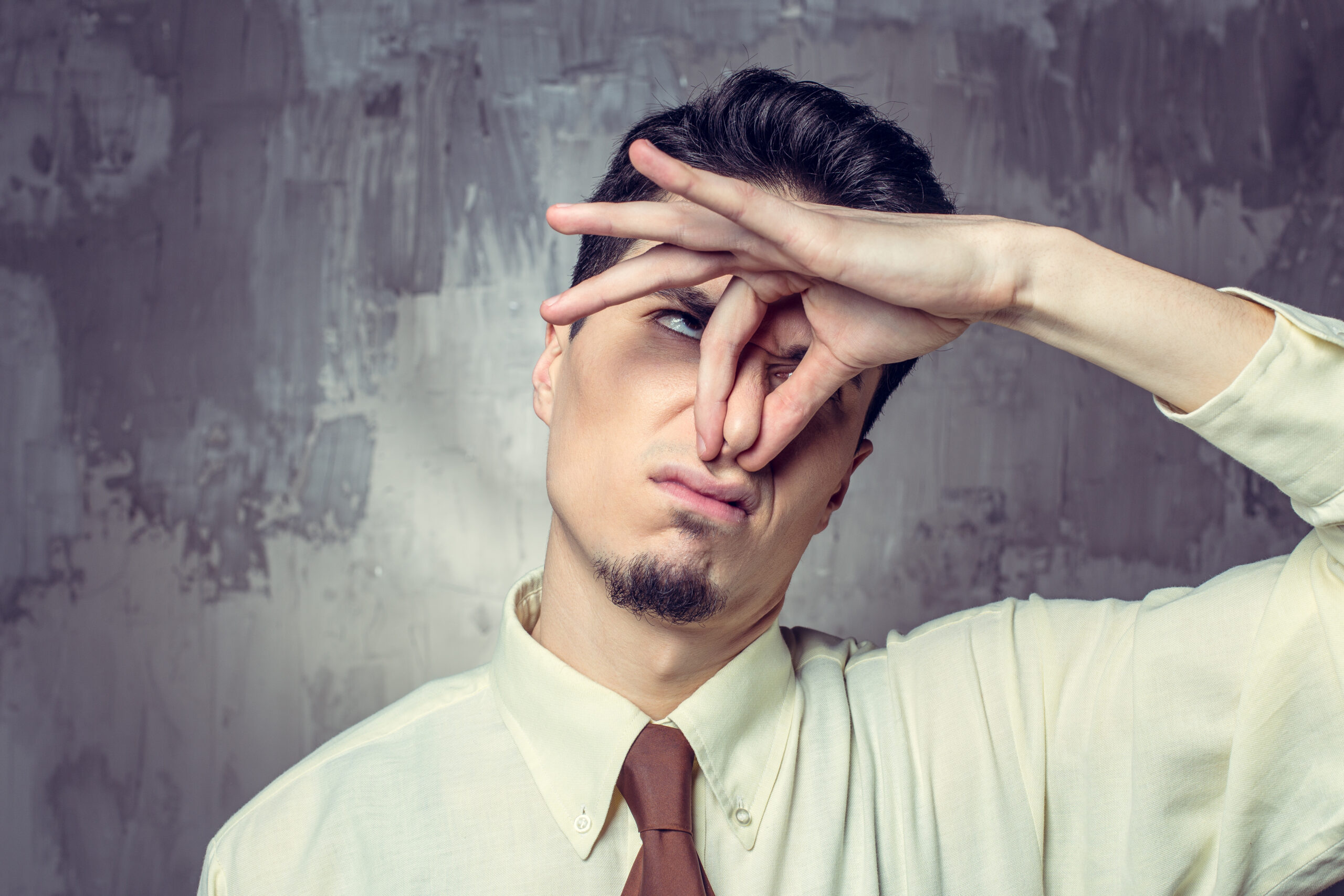 Young man closing nosa against stinky smell La maîtrise des odeurs est essentielle : elle améliore la qualité de vie, favorise la productivité et renforce l’expérience client.